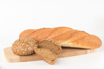 Wheat baguette and wholegrain bun on a cutting board isolated on white - 559361486