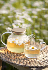 Obraz na płótnie Canvas Vertical photo of glass teapot and a cup of herbal camomile tea
