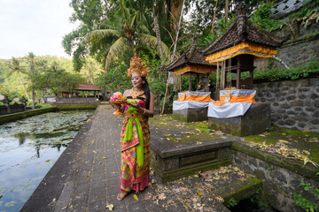 Obraz premium Portrait of a Balinese dancer in a colorful costume with gold crown in a dance position at a temple
