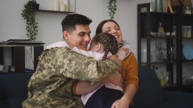 Happy military man and wife hugging and kissing little daughter, family love