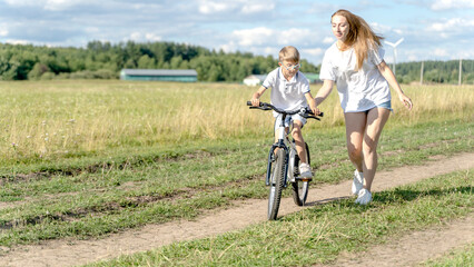 Obraz premium loving mother help her cute son ride a bicycle