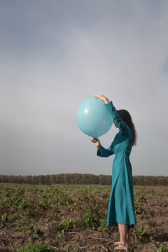 hold on or let go: woman in blue dress holding large balloon in nature