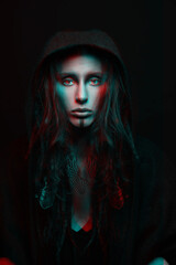 Beautiful woman studio portrait in red and blue color split effect. Model with dreadlocks hiding under hood and looking to camera with seductive look. Futuristic looking style