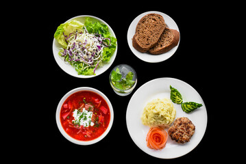 Combo set with borscht, mashed potato, black bread, salad on black background top view