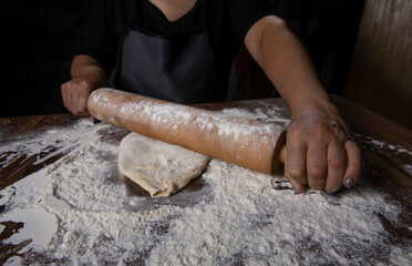 Chef is rolling the dough with the rolling pin on the on the table. Hands close-up.Cooking pasta, bread, spaghetti, khachapuri, food concept