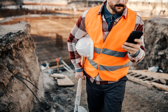 Cropped picture of a site worker using a phone while walking on site.