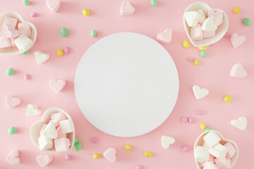 Obraz na płótnie Canvas Valentines concept. Flat lay photo of heart shaped saucers with candies and heart marshmallow on pastel pink background with card note in the middle. Sweet Valentines card idea.