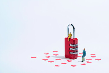 Obraz premium a young woman sits on a red padlock and looks down at her partner, white background with red hearts. Valentine's day holiday concept