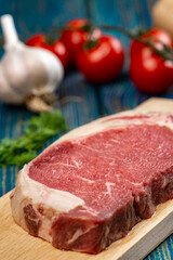 raw beef steak with vegetables and spices on wooden table