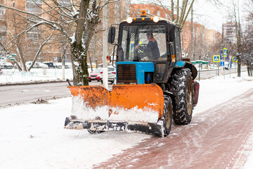 The blue tractor is moving backwards. Snow plow tractor. Clearing streets and roads from snow....