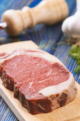 raw beef steak with vegetables and spices on wooden table