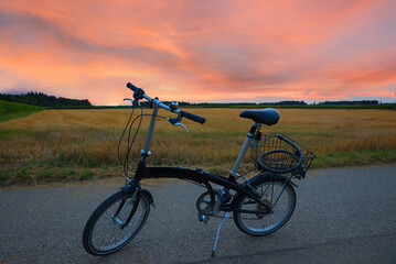 Obraz premium bike tour with folding bike along the fields at sunset
