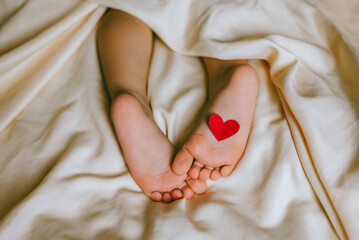 Children's feet and heels with heart on a white bed to Christmas, Valentine's day, Mother's Day....
