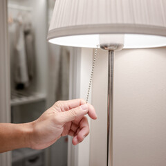 Male hand turn off the light on torchiere lamp in bedroom. Saving electricity energy at night. Switch off lighting equipment for bedtime.