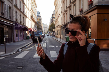 Young lady using smartphone on Paris streets.
