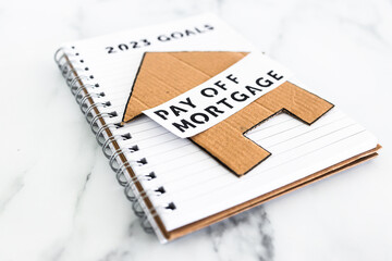 financial independence and being free from debt, 2023 goals on notebook with cardboard house and Pay Off Mortgage text