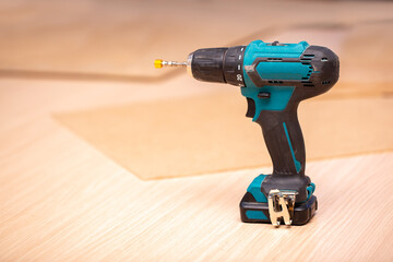 Electric cordless drill driver on the background of a carpentry shop, a professional tool for home repair, a hand power tool, copy space.
