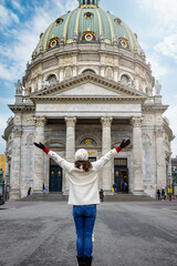 A tourist woman on a sightseeing tour stands in front of the famous Frederiks Church in Copenhagen, Denmark