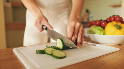 Close-up of young woman's hands cutting tomatoes making salad at home in the kitchen