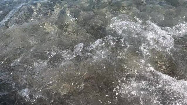 agua del mar en la orilla del la playa con olas rompiendo salpicando espuma de mar