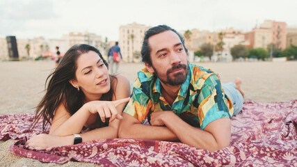 Man and woman talking and relaxing on blanket on the beach