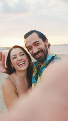 Laughing couple making video call while standing on the beach