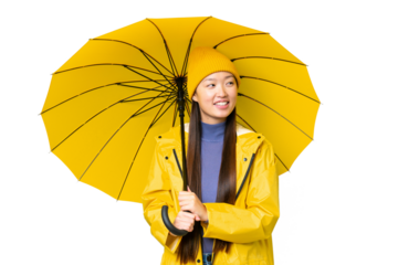 Young Asian woman with rainproof coat and umbrella over isolated chroma key background looking side