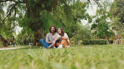 Happy smiling couple talking while sitting on blanket in park