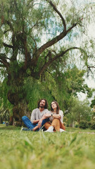 Happy smiling couple talking while sitting on blanket in park