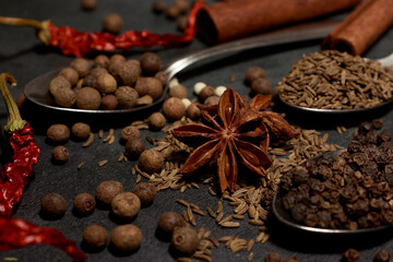 A set of different spices close-up on a dark table. Spice background. Banner. Oriental spice market. A set of peppers and spices for cooking. Indian spices set.