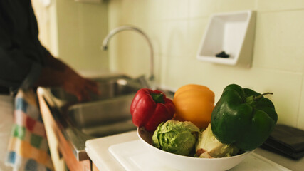 In the foreground, vegetables, in the background the hands of man washing vegetables the background. soft focus