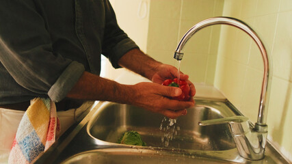 Close-up of man's hand washing vegetables in the kitchen