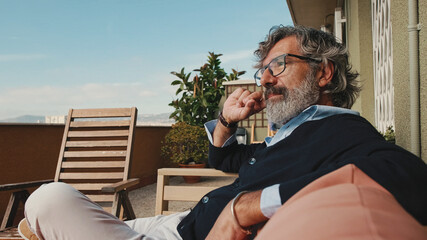 Middle-aged man enjoying sunny weather on the balcony