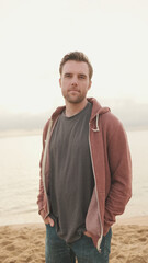 Close-up of young man standing on the shore and looking at camera