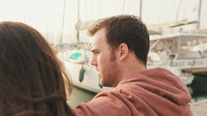 Couple sitting in the port looking at the yachts. Back view