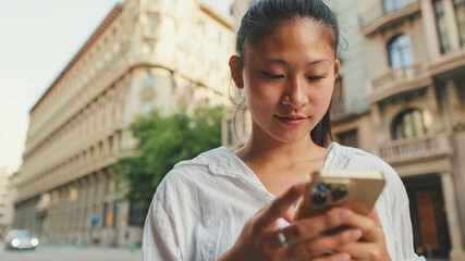 Young smiling woman using mobile phone while standing next to the road