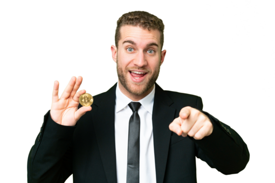 Young business blonde man holding a Bitcoin over isolated chroma key background surprised and pointing front