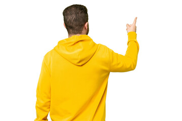 Young photographer man over isolated chroma key background pointing back with the index finger