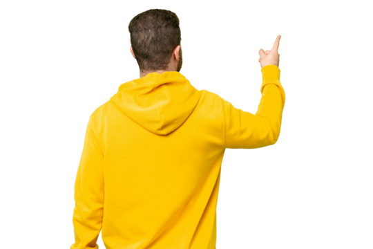 Young photographer man over isolated chroma key background pointing back with the index finger