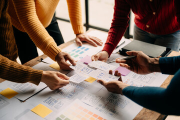 Close up view of UI developer team brainstorming on their project with laptop, smartphone and...