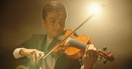 Experienced Violinist performing amazing solo on stage, spotted by light on black background close...