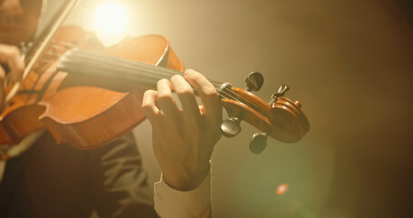 Experienced Violinist performing amazing solo on stage, spotted by light on black background close...