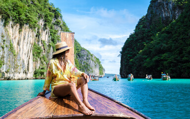 Asian women in front of a longtail boat at Kho Phi Phi Thailand, women in front of a boat at Pileh Lagoon with turqouse colored ocean - obrazy, fototapety, plakaty