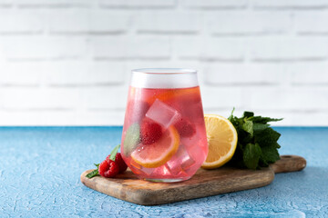 Raspberry lemonade drink in glass on blue background