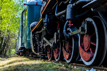 Close-up of the driving wheels of a steam locomotive. Steam locomotive parked on the forest station.