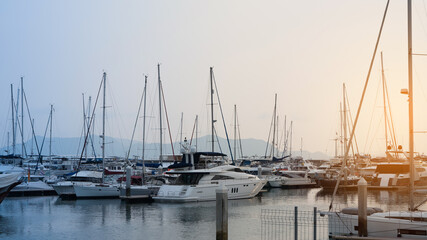 a lot Fashionable Luxury yachts docked in sea port at sunset for Vacation. Marine parking of modern motor boats and blue water.