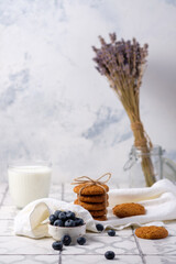 Fresh grandmother's oatmeal cookies with milk and berries on a linen napkin in the village.