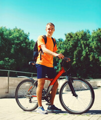 Naklejka premium Sport, leisure and healthy lifestyle concept - young man on bicycle in summer park on blue sky background, male cyclist in the city