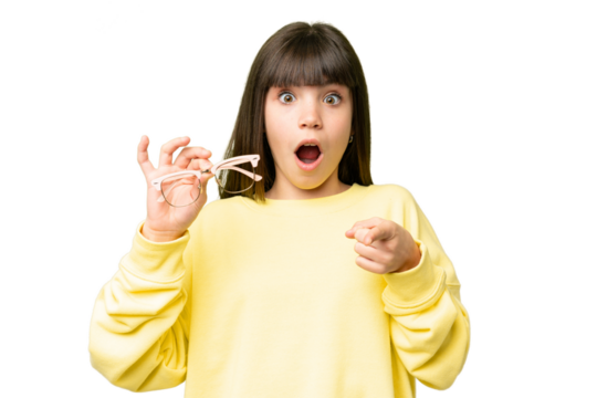 Little girl with glasses over isolated chroma key background surprised and pointing front - Powered by Adobe