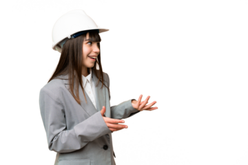 Little girl playing as a architect with helmet and holding blueprints over isolated background with surprise expression while looking side